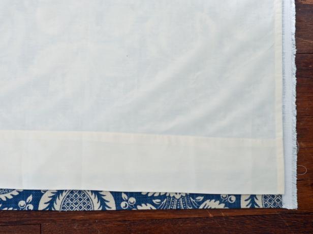Spread fabric on floor or work surface, right-side facing down. Place twin bed sheet/lining on top, right side facing up and top of sheet at bottom of panel to act as a hem. Line up bottom of lining about 1 inch higher than bottom of fabric panel. Smooth both fabrics out, removing all wrinkles and folds .