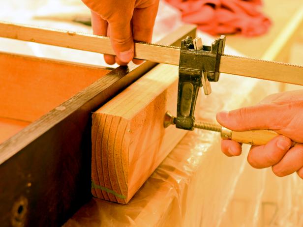 A vintage dresser drawer is clamped to set glue after being cut for use in a DIY bathroom vanity.