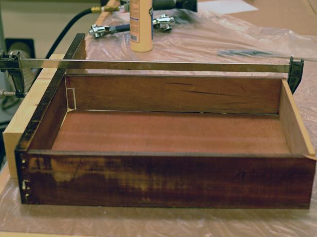 A drawer from a vintage dresser is clamped to aid in glue drying after being cut for use in a bathroom vanity.