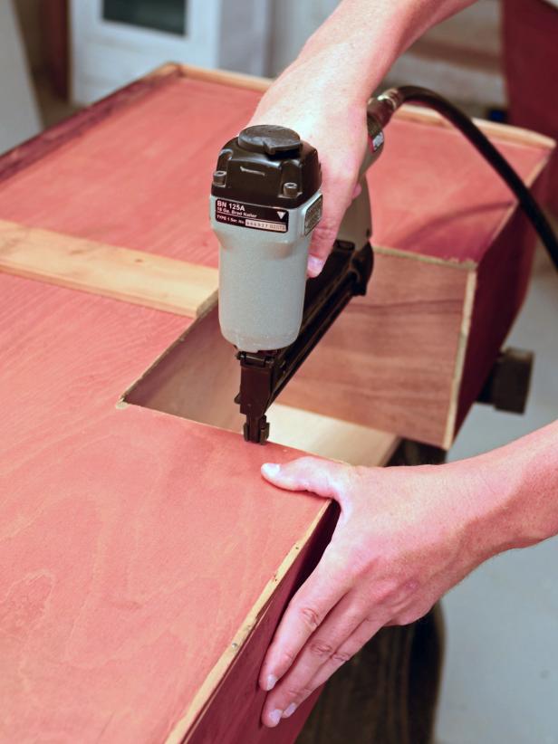 A vintage dresser is readied to be turned into a bathroom vanity as plumbing recesses are cut into its drawers.