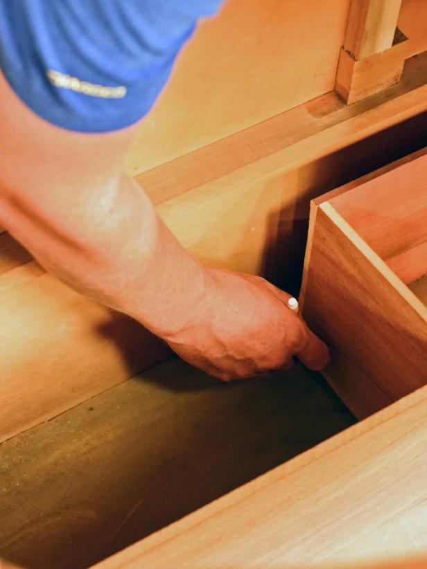 A drawer in a bathroom vanity custom built from a vintage dresser is measured for fit.