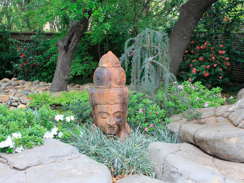 Garden With Statue of Buddha's Head, Green Foliage Plants and Boulders