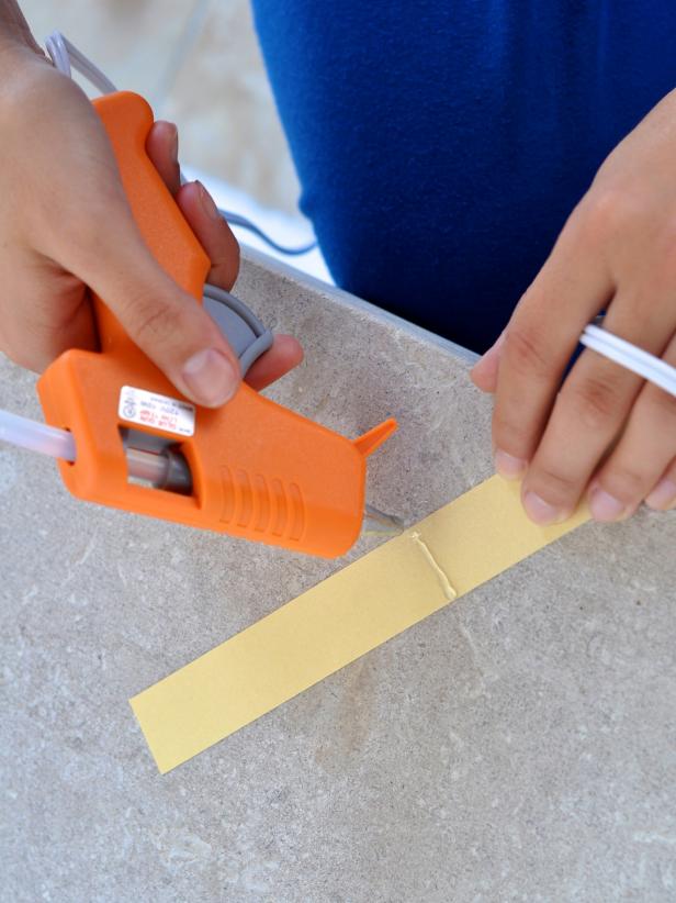One of the first steps is to heat up your hot glue gun. Add a line of hot glue to back of paper strip.