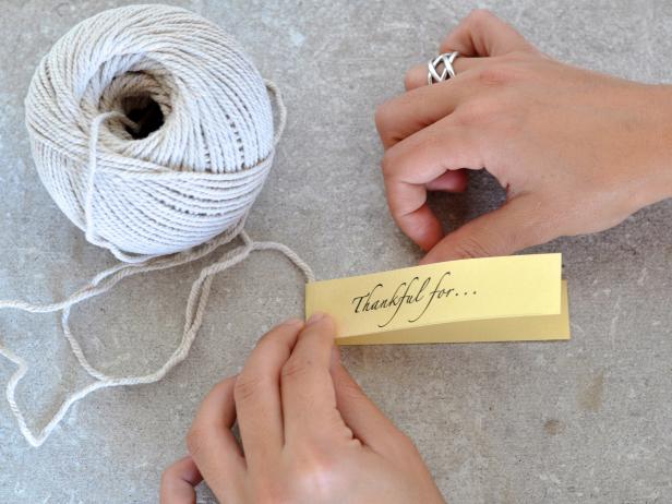 Fold over the card stock strip to meet taped side and press to seal keeping the string inside the crease. Repeat with remaining paper strips, adding a paper strip about every five inches, alternating colors as you go.