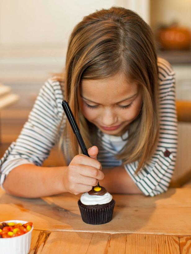 Use the black edible-ink marker to draw 2 small dots on the yellow candy for the turkey's eyes, leaving space for the turkey's beak.