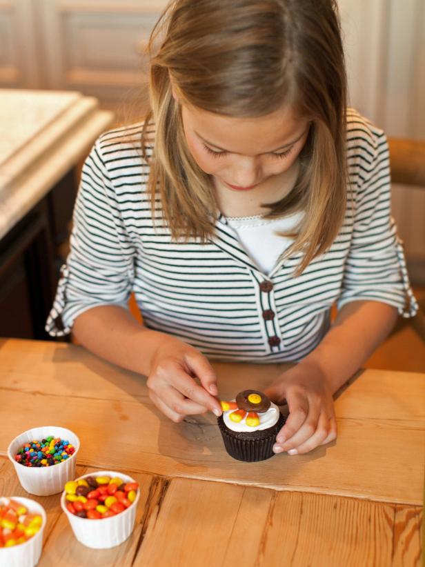 Add 5 candy corns to the top half of the turkey, resting them on the white frosting with the candy's white tips beneath the chocolate frosting