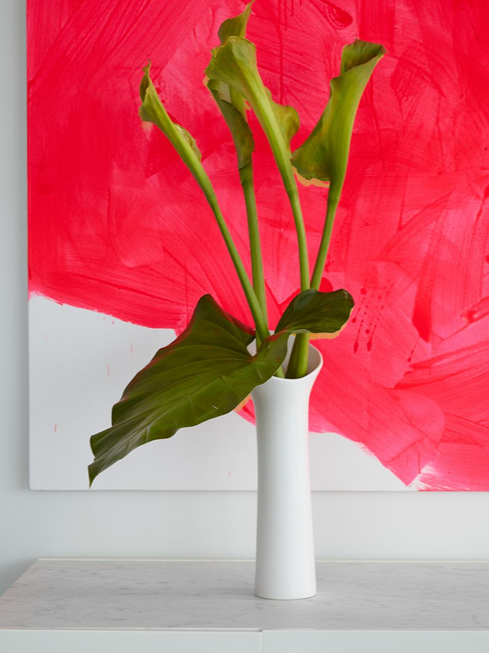 Pink Artwork Behind White Vase With Green Plant