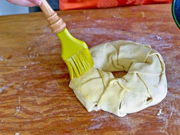 Apply egg wash to the cheese and herb wreath pastry.