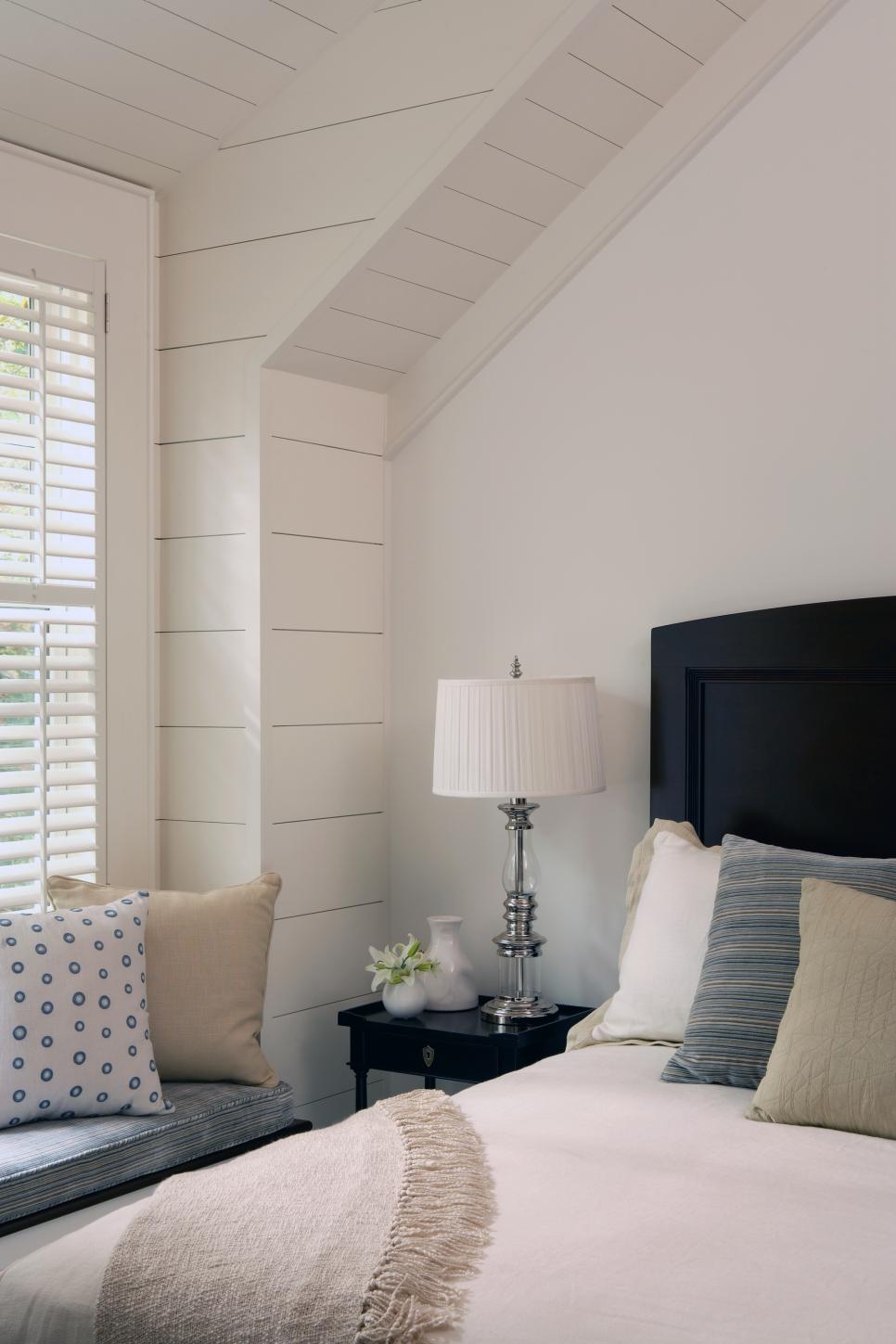 Cottage-Style Bedroom With Wide Plank Paneling White Bedroom With Paneled Wall, Wood Shutters & Window Seat