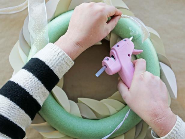 Step 9b: Affix the ribbon to the back of the wreath with hot glue, then tie the ends together and hang.