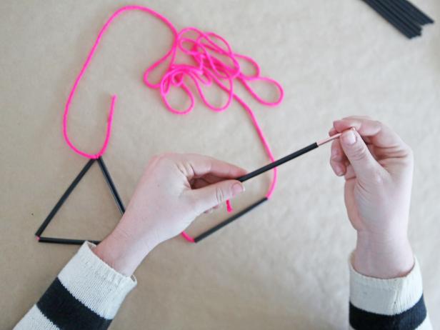 Step 5: Add another straw piece, tying off at the tip of the triangle.