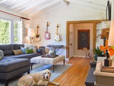 White Living Room With Gray Sectional, Large Dog, Guitars on Wall