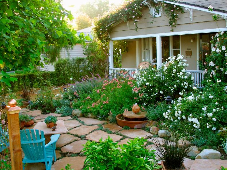 Beige House With Front Yard Garden, Stone Walkway and Blue Chairs