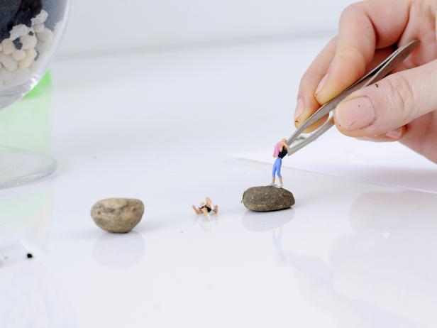 Pick out a flat rock for your figures to stand on — look for small rocks in your yard. Dip the feet of your first figure in waterproof glue, and attach to the flat rock.