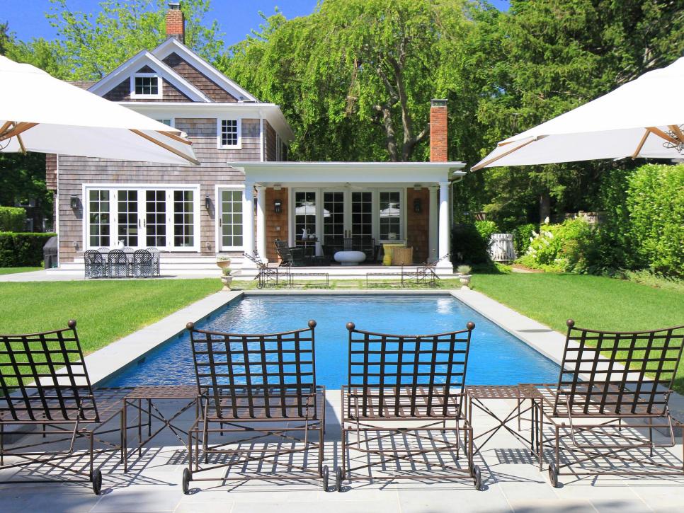 Exterior of Gray Cape Cod House With Pool and Lounge Chairs