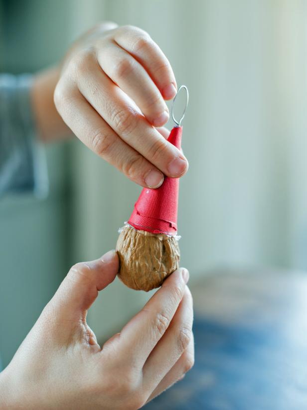 Glue the small paper hat onto the walnut to create the ornament.