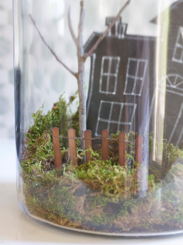 To create a spooky Halloween terrarium, cover the bottom in moss. Cut a haunted house out of tag board and attach to the inside with tape. Add a cute ghost made from a 1’foam ball wrapped in tissue. Push a length of miniature fence into the moss near the front of the jar. Add additional texture with clumps of reindeer moss, then place lid on top of the jar, adjusting the fishing line's length, if necessary, so the ghost hangs at the right level.