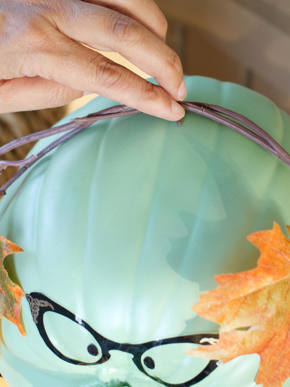 Finishing Touches Person attaching craft leaves to pumpkin