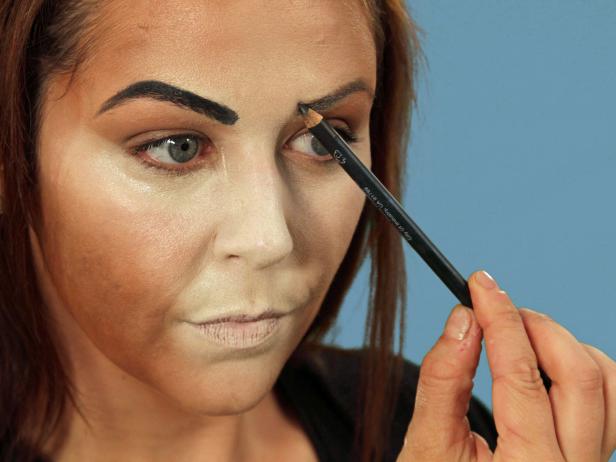 For enviable Halloween cat makeup, get the perfect base by using a makeup sponge to apply foundation that is several times lighter than your skin to the nose, middle of the forehead, under the eyes, along the cheeks and down the chin. Use a different makeup sponge and apply dark orange-brown foundation to all the areas not covered by the light foundation. Use a third sponge and lightly blend where the two colors meet. Use black eyeliner to fill in the brows. Add sharper angles over the middle of the eyes to create a dramatic peak. Heavily line the bottom lash line and extend the line out past the eye. Inside, extend the line a little down the inside of the nose. Line the top lash line and on the inside corner of the eye. Extend the top line to meet the bottom line. With the pencil, cover the eyelid, extending out beyond the eye. Blend the lines with a small, flat makeup brush to make them smooth.
