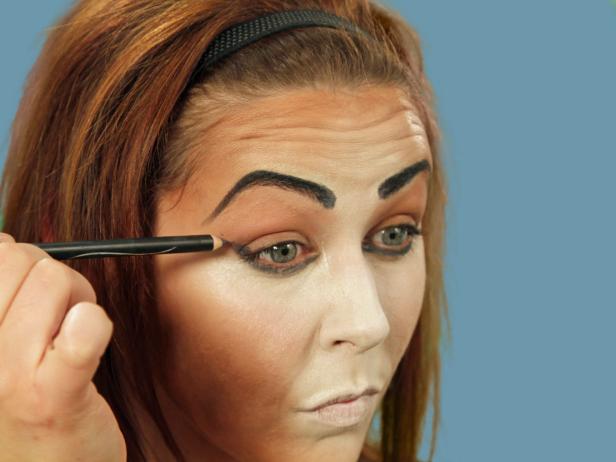 For enviable Halloween cat makeup, get the perfect base by using a makeup sponge to apply foundation that is several times lighter than your skin to the nose, middle of the forehead, under the eyes, along the cheeks and down the chin. Use a different makeup sponge and apply dark orange-brown foundation to all the areas not covered by the light foundation. Use a third sponge and lightly blend where the two colors meet. Use black eyeliner to fill in the brows. Add sharper angles over the middle of the eyes to create a dramatic peak. Heavily line the bottom lash line and extend the line out past the eye. Inside, extend the line a little down the inside of the nose. Line the top lash line and on the inside corner of the eye. Extend the top line to meet the bottom line. With the pencil, cover the eyelid, extending out beyond the eye. Blend the lines with a small, flat makeup brush to make them smooth.