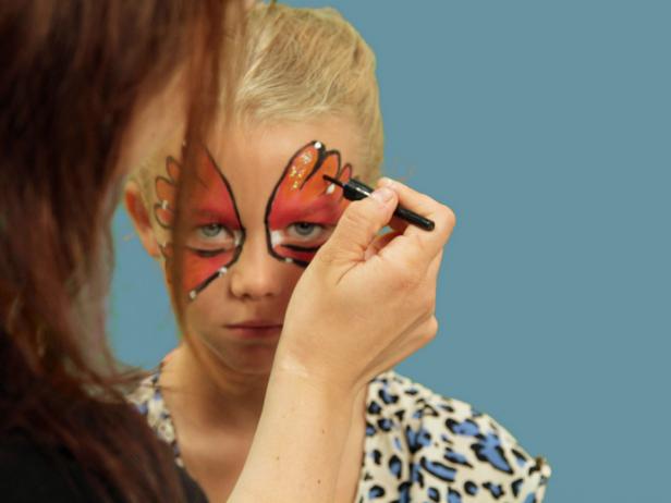 To transform your child or yourself into a beautiful butterfly for Halloween, create one large wing over each eyelid and up the forehead using face paint and a wide brush. Use black liquid eyeliner and line the edge of the makeup. To add highlights to the wings, use white face paint and a small makeup brush to randomly dot white on each wing tip, right on top of the black lines. Also, add a dot to the inside of the eye. Use your fingers and carefully apply some kid-friendly gel glitter inside the black lines on the wings. Be sure to keep the glitter away from the eyes.