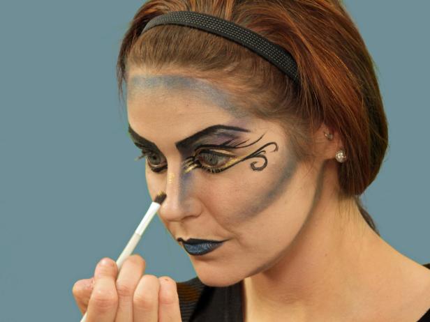 With an eye shadow brush, add gold metallic eye shadow to both the lower eyelids and the corner of the eyes, as well as the bridge of the nose and the center of the forehead.