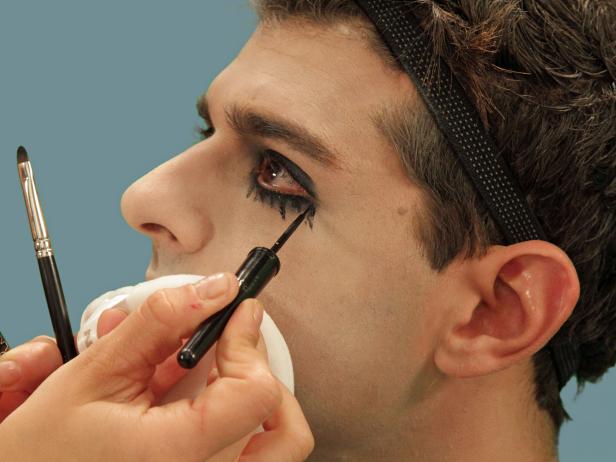 Use black liquid eyeliner to draw random vertical tear lines from the bottom eye. Use a flat brush to blend while the liner is still wet