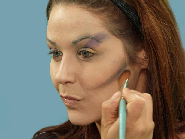 .Add contours to the face using a medium makeup brush to apply blue metallic eye shadow under the cheekbones.