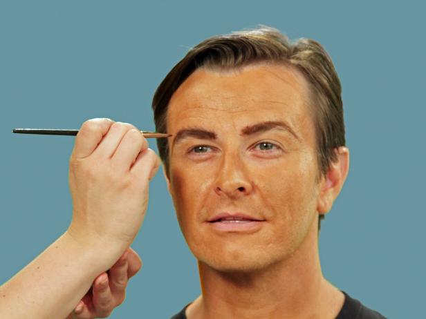 Woman applying Halloween pirate makeup to man