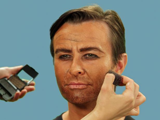 To give your pirate beard growth, dip the stipple sponge into black and brown cream makeup, then lightly dot onto the face. Add age spots and an uneven skin tone using the stipple sponge, dabbing gray and brown eye shadow onto the forehead and cheeks.