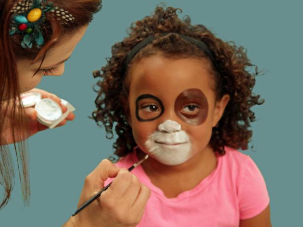 After you use white paint to create a puppy snout, use a detail brush to pull the face paint out in thin strokes to create the muzzle's shape.