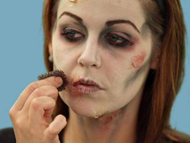 After creating fake scars, add detail to make the wounds look real. With a stipple sponge, add some depth by adding red, black and gray shadow in and around the infection sites.