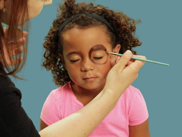 Make the perfect puppy eyes by using a medium makeup brush to apply brown face paint, making a giant circle around one eye, extending up and over the eyebrow. Fill in the circle, but be careful not to get too close to the eye with makeup.