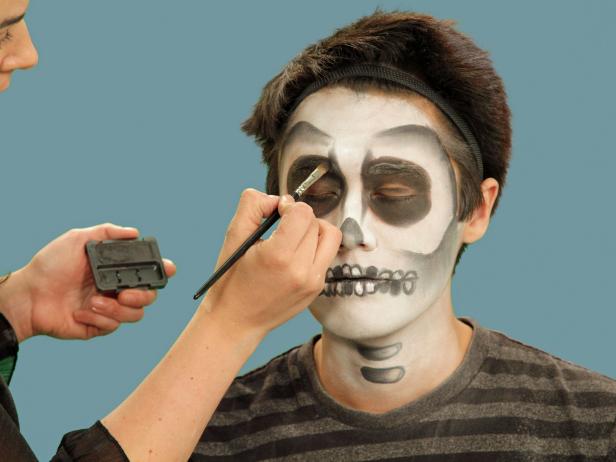 Setting makeup with translucent powder can sometimes soften darker colors. If any of the dark tones dulled after the powder has been brushed away, use an eye shadow brush and black and gray shadow to reinvigorate the shaded areas. Just be certain not to use any more cream makeup once the face is powdered.