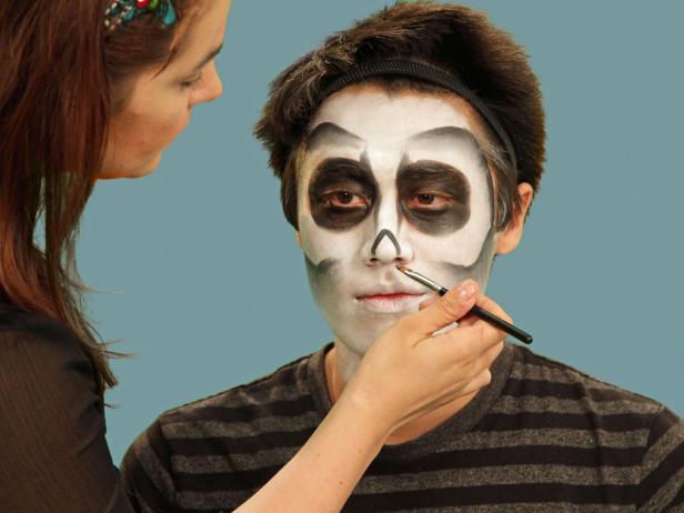 Use a small brush to draw the skeleton nose. Draw a triangle just over the tip of the nose and blend downward, making certain to leave the very tip of the nose white.