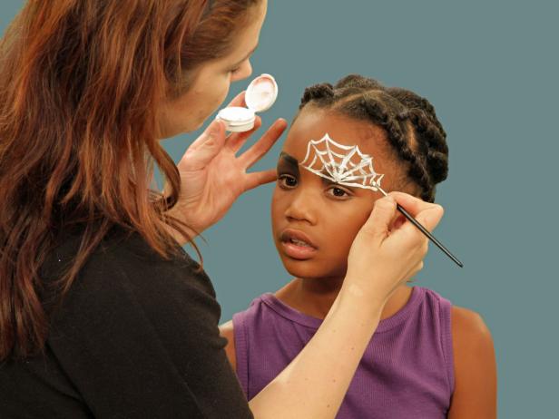 Make a spider web eye for fun Halloween spider makeup. On one eye, create a spider web. Using white face paint and a thin craft brush, start just above the crease in the eyelid and draw lines up and outward. Connect them with one line that dips down between each point.