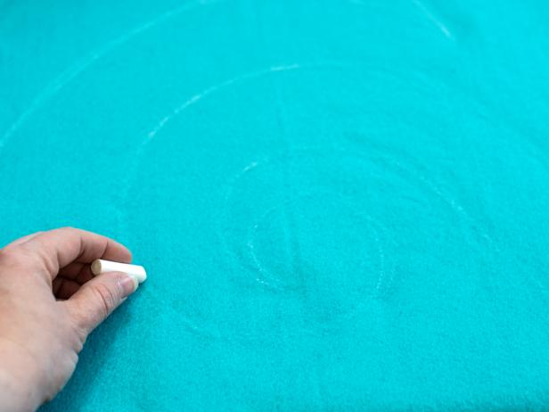 Fold turquoise felt for tree skirt into quarters and sketch a large, simple design in chalk onto felt.