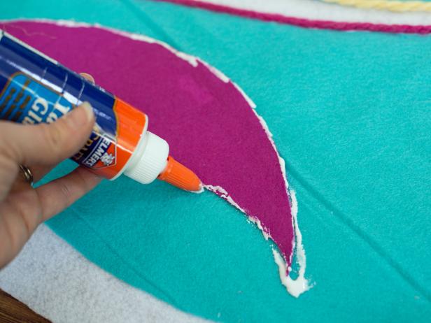 Apply a bead of fabric glue along edges of tree skirt's felt design then top with chunky yarn in coordinating colors.