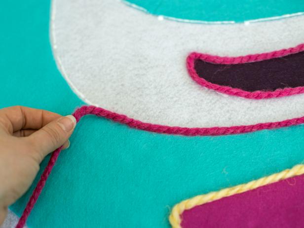 Apply a bead of fabric glue along edges of felt design then top with chunky yarn in coordinating colors. The yarn adds color and texture to the design and hides raw edges of the felt, making the tree skirt look more polished.