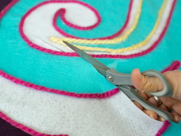 In Step 1, a slit was cut in the white felt tree skirt base before the design was created over it. Now, cut through design, along the previously cut slit, so the skirt can be easily placed around the base of your Christmas tree.