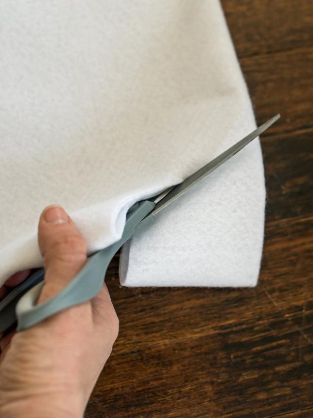 Cut along measured pencil line, then cut corner where folds meet in a quarter circle pattern to create a hole in tree skirt for tree trunk.
