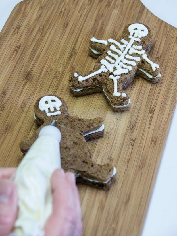Begin making the skeletons on top of the sandwiches from the top down starting with the skull, leaving holes for the eyes and a few teeth.