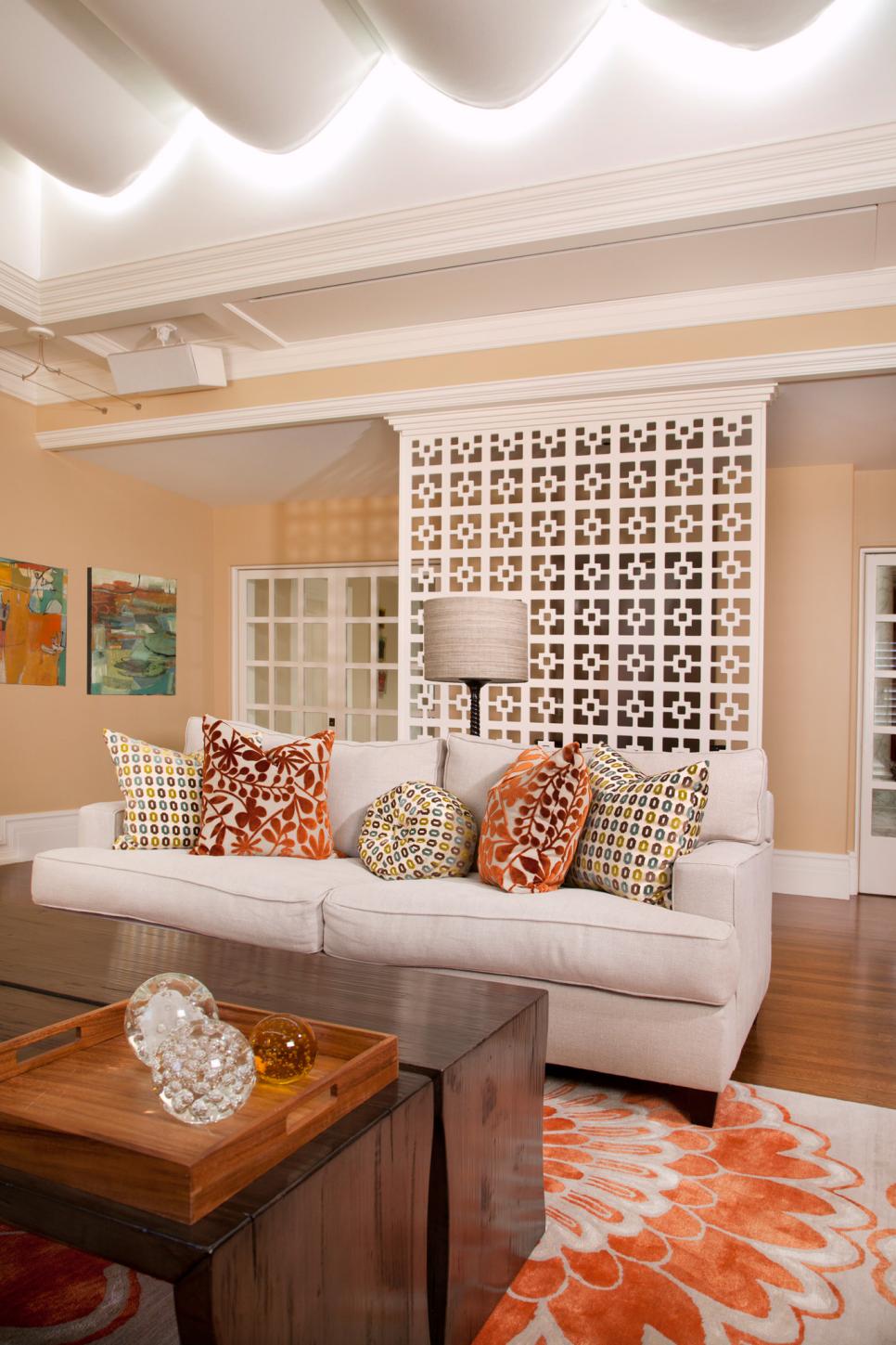 Living Room With White Screen, Sofa, and Orange Floral Rug and Pillows