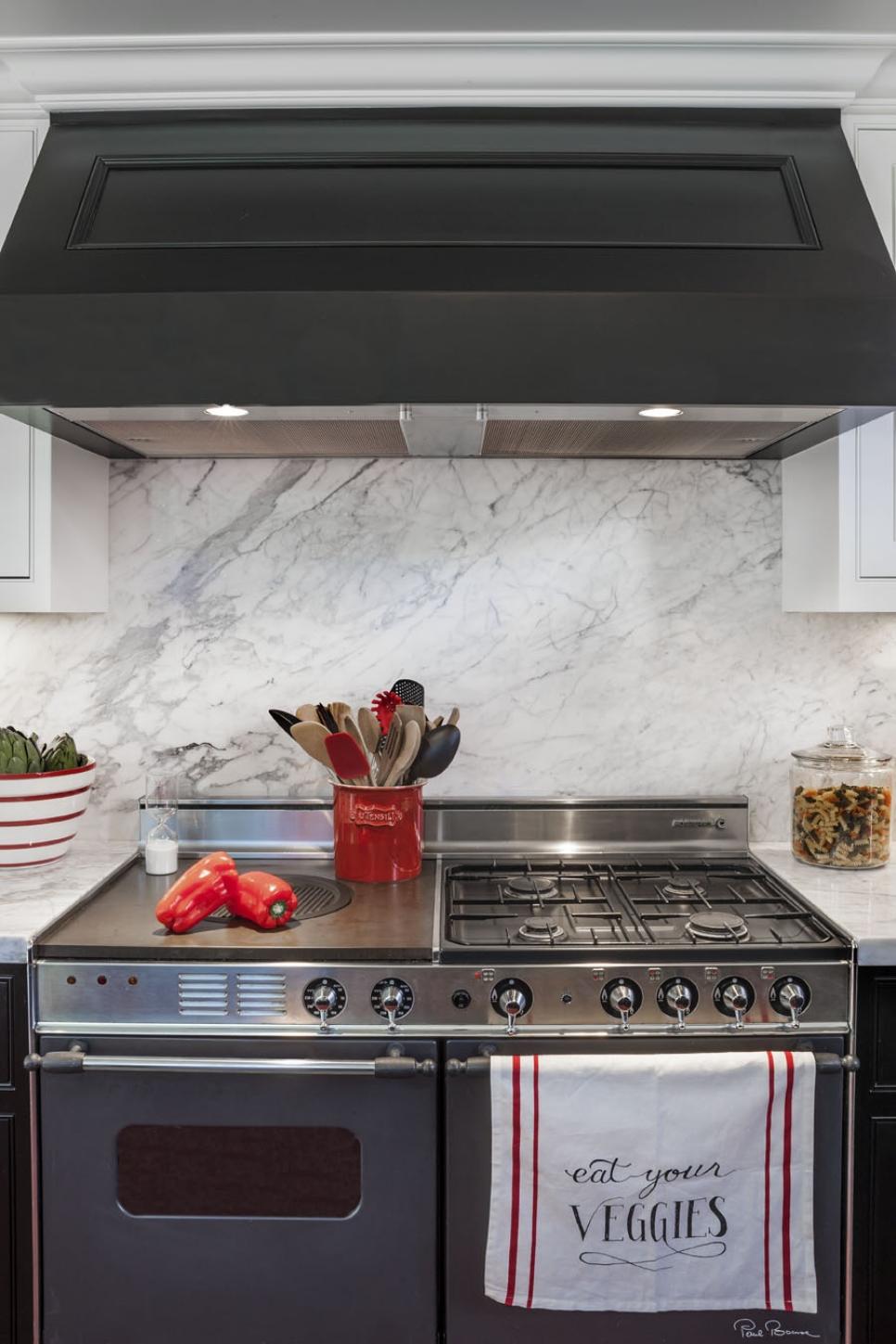 Kitchen With Black Range Hood, Marble Backsplash and Stainless Oven