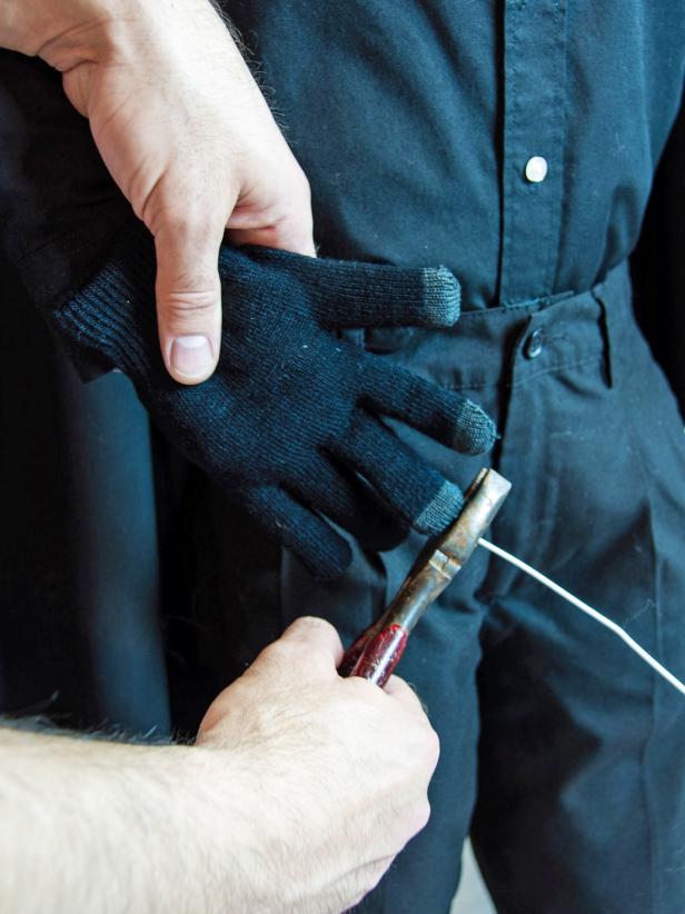 Add folded up tissue paper as the palm and back of the hand. Push the filling on one of the wires up into the sleeve. Bend the wire where the elbow would be. Insert the bottom of the glove into the sleeve. Measure it against the wire at the tip of the middle finger and cut the excess wire off.