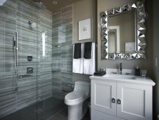 Floor-to-ceiling marble and reflective geometric surfaces punctuate this modern guest bathroom.