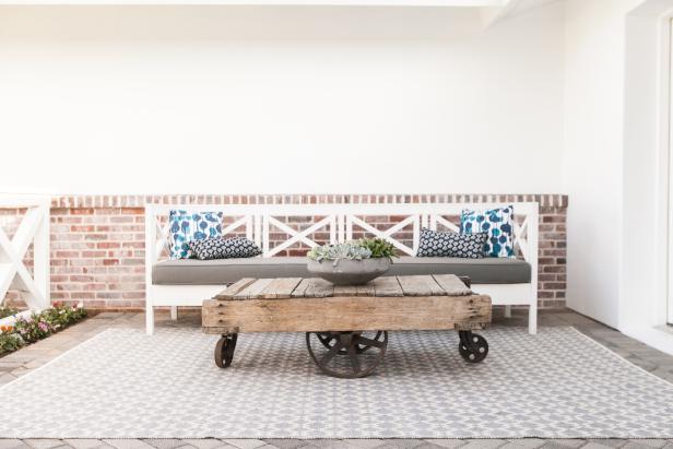 Front Porch Sitting Area With White Bench and Rustic Table