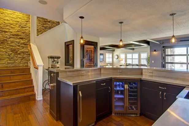 Basement Wet Bar With Industrial Lighting and Nearby Staircase