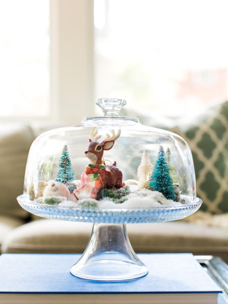 Add instant space for holiday decorations by repurposing a clear glass or acrylic cake stand as a makeshift snow globe. Arrange different holiday figures with moss or faux snow to create the look of a winter scene.