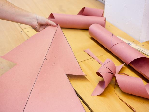 Using a straight edge, mark the center line of the tree at desired height. Next, draw one half of the tree onto the craft paper Once complete, fold paper along the center then cut out using scissors, Unfold and your symmetrical template is complete